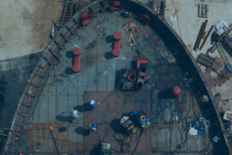 Vista aerea di un cantiere industriale con operai al lavoro su una struttura metallica, illustrando la gestione asset cantieri.